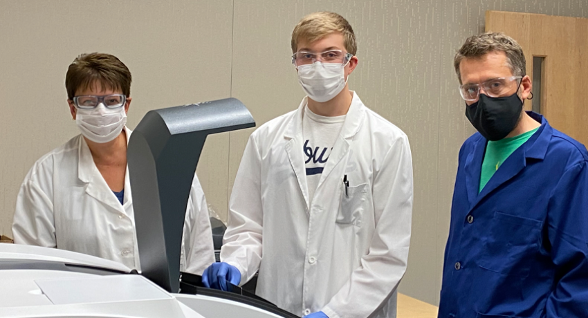 Connor Mosebey (center) loads a materials sample into a UV-Vis spectrometer