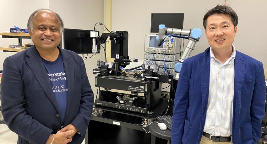 Two men standing in front of a large machine in a lab